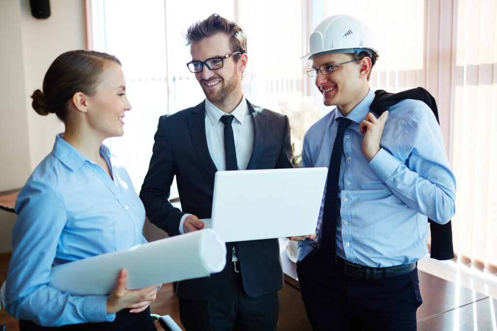 Construction project managers and engineers discussing workforce plans with digital tools in a modern office setting.