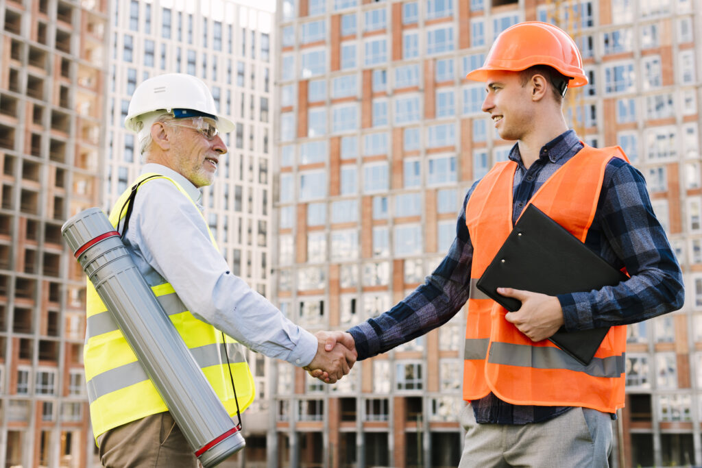 Two construction professionals wearing safety gear shake hands on site, symbolizing reliable labour construction Canada 2025 and strong workforce partnerships.